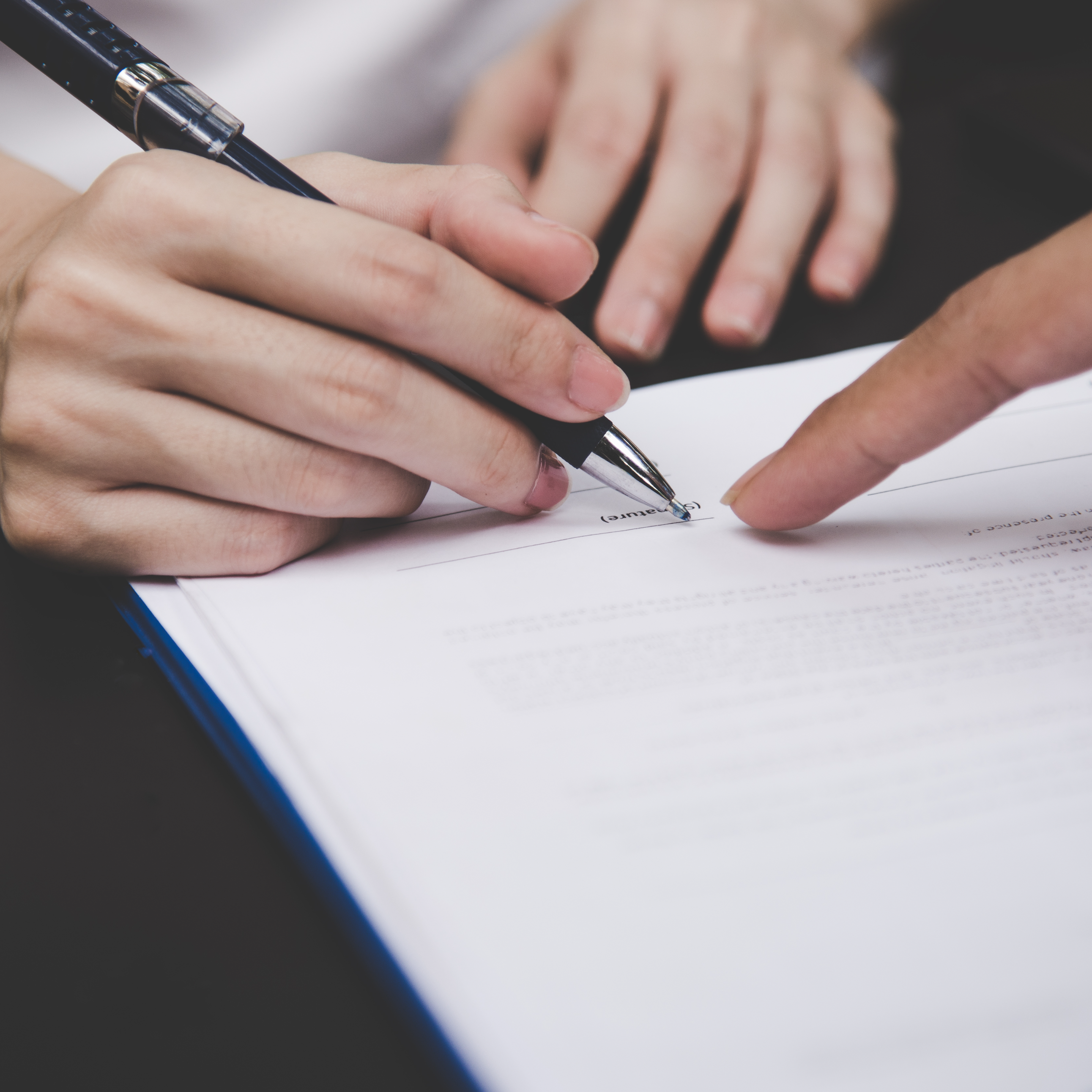 Hand holding pen about to sign document
